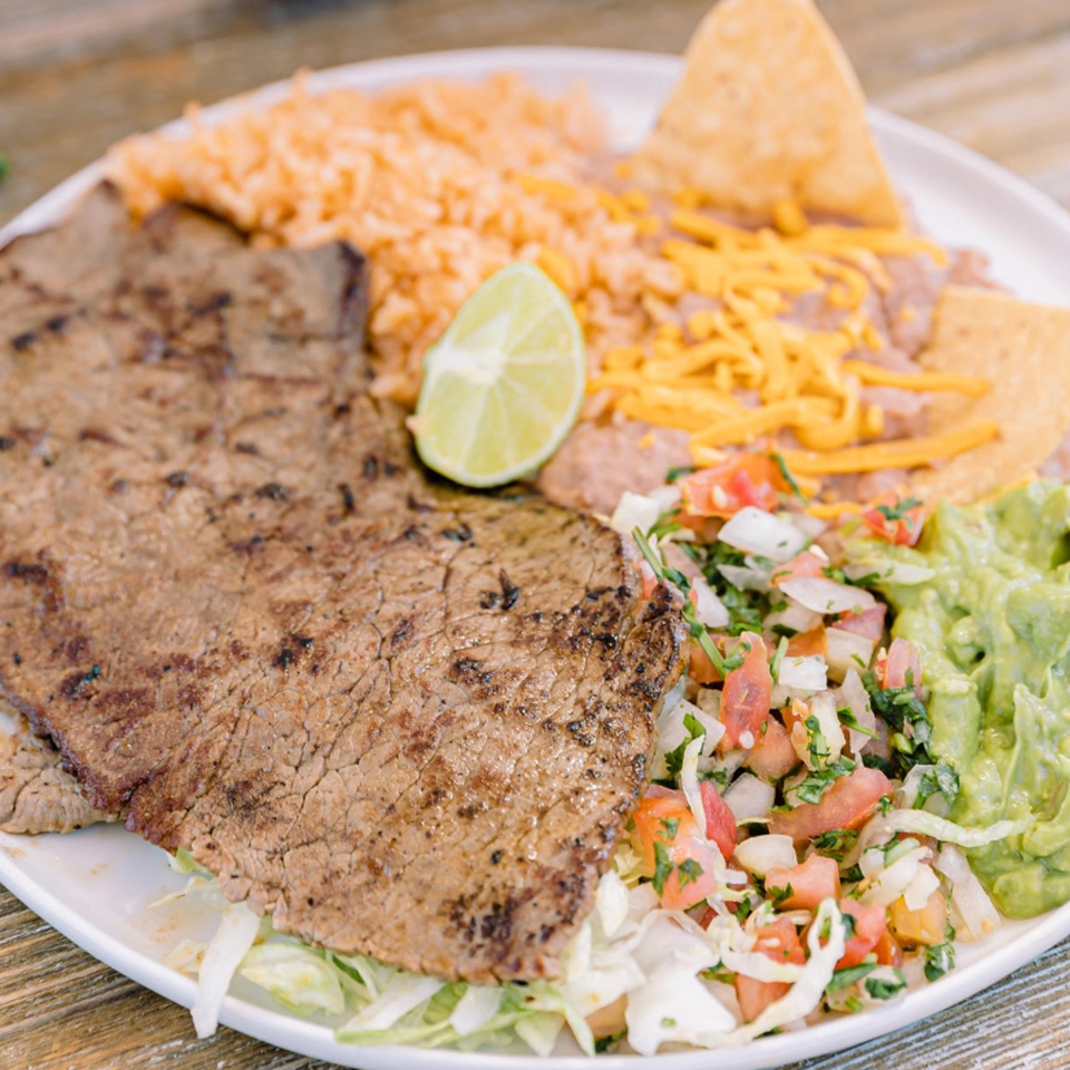 Adalbertos Mexican Food's carne asada plate with rice, beans, guacamole, pico de gallo, and a lime.