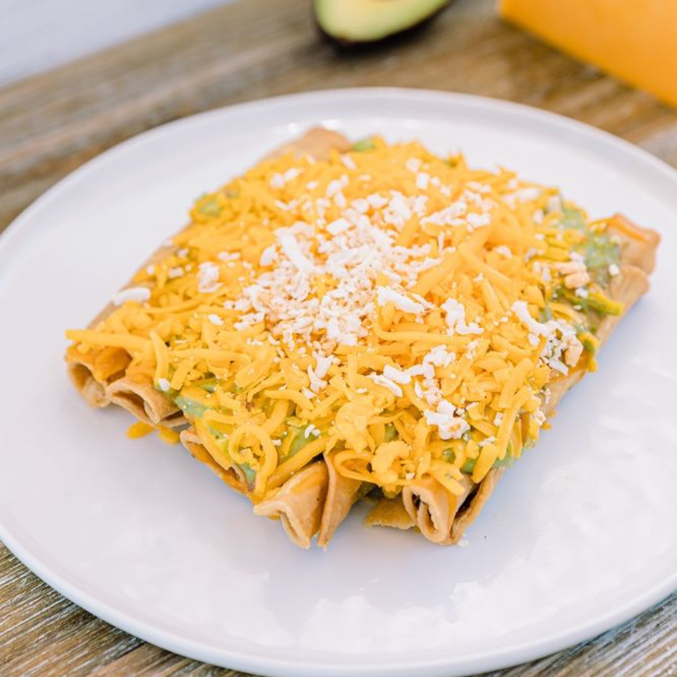 Adalbertos Mexican Food taquitos topped with shredded cheddar and cotija cheese, and guacamole.